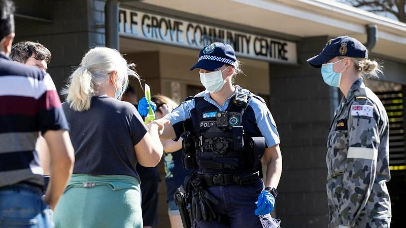  NSW Police Constable Megan Green and Seaman Jordan Parsons hand out sunscreen to civilians waiting in line for a COVID-19 test at the Wattle Grove Community Centre. Photo: Corporal Dustin Anderson 