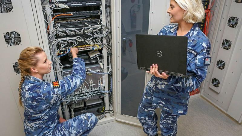 Aircraftwoman Lauren Campbell, left, with Corporal Natalie Ekonomopoulos in a communications cabinet for cyber research and development systems at No. 462 Squadron. Photo: Corporal Brenton Kwaterski