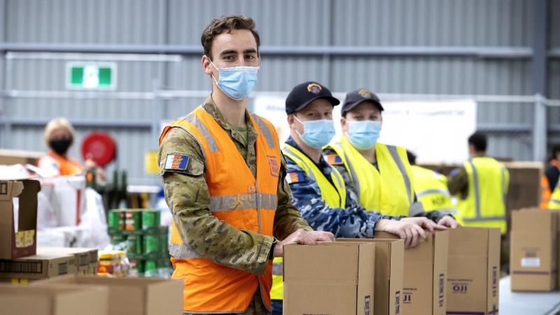 From left, Lieutenant Hugh Manson, Aircraftman Zac Fraser and Able Seaman Renee Shultz assist Foodbank volunteers prepare food hampers for communities affected by COVID-19. Photo: Corporal Dustin Anderson
