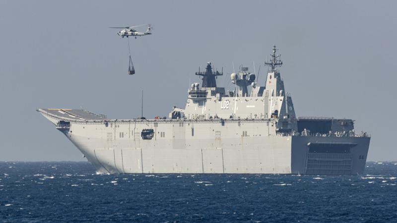 HMAS Anzac's embarked MH-60R collects a desalination plant from HMAS Canberra for delivery to the Balinese island of Nusa Lembongan during IPE21. Photo: Leading Seaman Leo Baumgartner