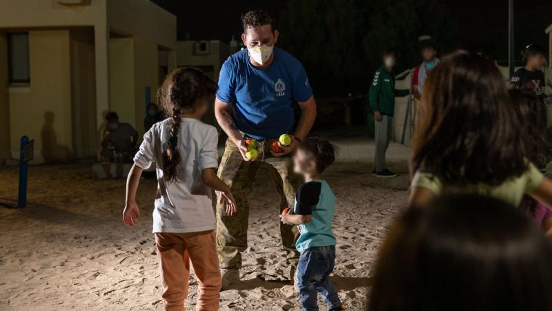 Private Ethan Wright, from 1 RAR, plays with Afghanistan evacuees at a temporary camp in Australia’s main operating base in the Middle East. Photo: Leading Aircraftwoman Jacqueline Forrester