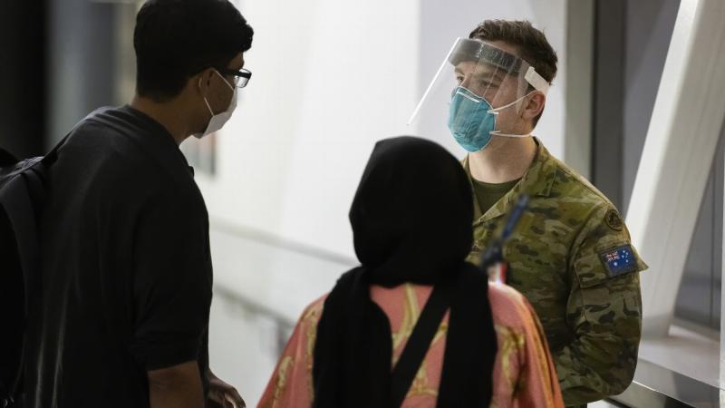 Private Jordan Schooth assists Australian citizens and visa holders evacuated from Afghanistan after their arrival in Australia. Photo: Corporal Dustin Anderson
