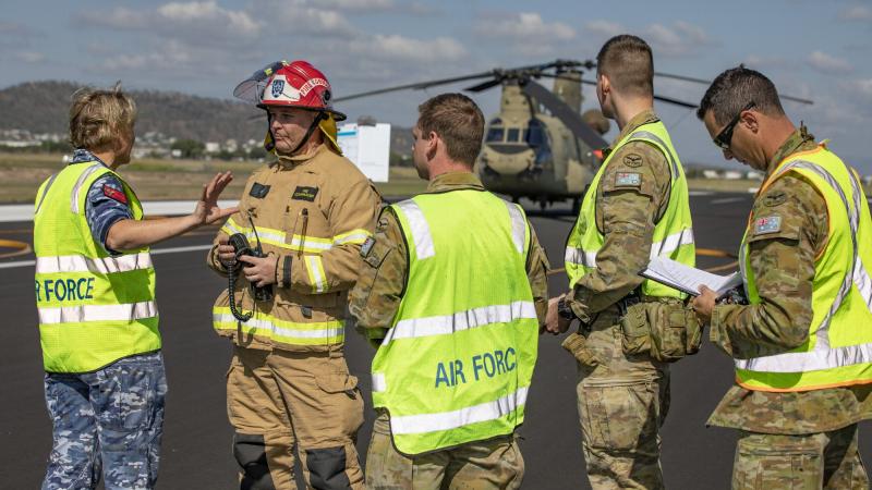 Medical officer Flight Lieutenant Melanie Smyth gives the fire commander from Aviation Rescue Fire Fighting Services and fellow Air Force members a situation report on the crash victims. Photo: Corporal Jesse Kane