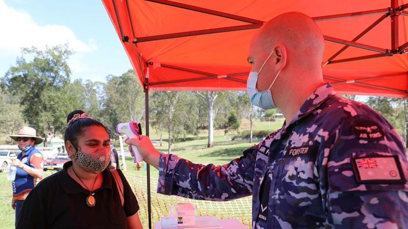 Malabugilmah resident Latia Williams has her temperature taken by Leading Aircraftman Joel Forster at a pop-up COVID-19 vaccination centre.
