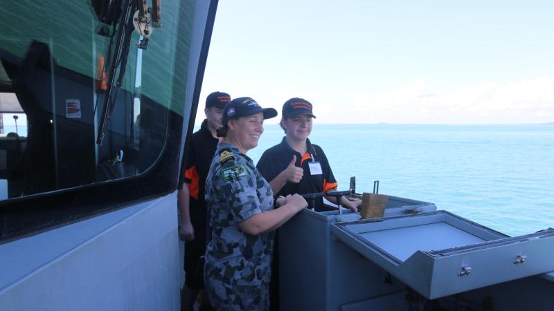 Commanding Officer HMAS Maitland Lieutenant Commander Julia Griffin shows Kyle Firgula-White and Alex Ryan how to drive the ship.