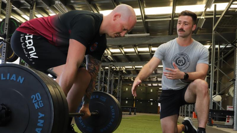 Australian Army avionics technician Corporal Simon Camilleri from 5th Aviation Regiment coaches a soldier through strength and conditioning techniques as a Combat Fitness Leader at RAAF Base Townsville, Queensland. Photo: Lance Corporal Lisa Sherman