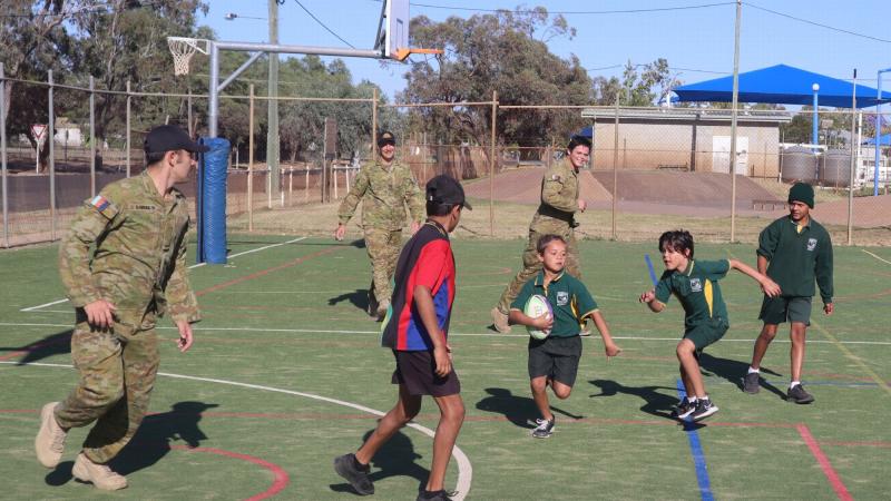 Private Robert Bayley, Corporal Jake Cobb and Private Harrison Britt play touch football with children at the Cunnamulla Breakfast Club.
