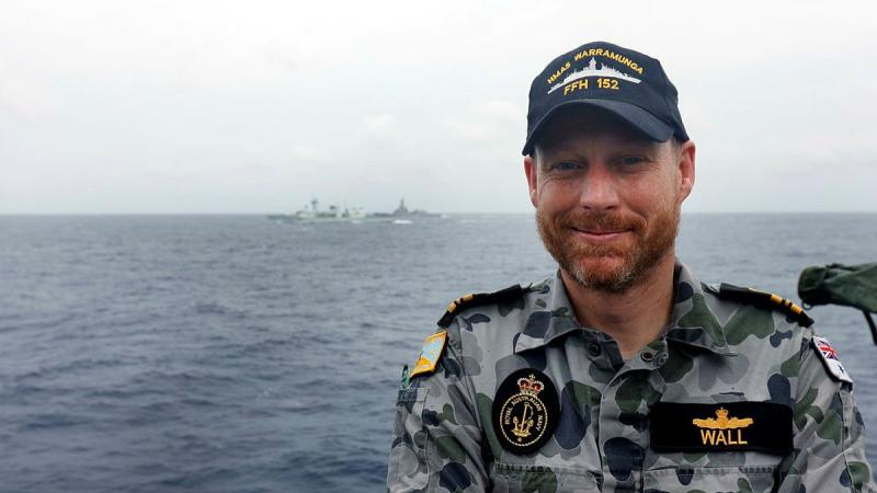 HMAS Warramunga's principal warfare officer and former Royal Canadian Navy officer, Lieutenant Commander Stephen Wall, with his former ship HMCS Winnipeg and HMAS Brisbane in the background. Photo: Petty Officer Yuri Ramsey