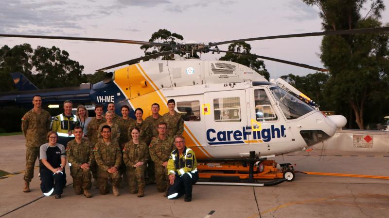 Members from the 3rd Health Support Battalion join Captain Paul Hanley (top, second from left), Ruth Parsell (bottom, first from left) and pilot Ian Smart (bottom, first from right) in front of the CareFlight rapid response helicopter. Photo: Duyen Nguyen