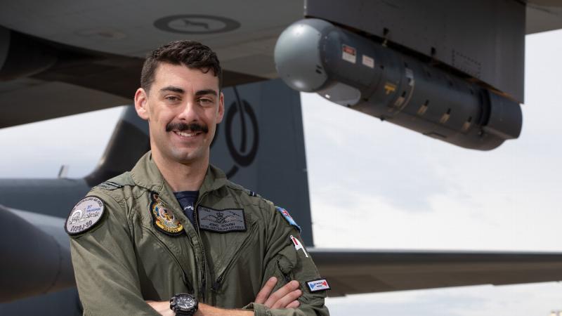 Flying Officer Johnathan Gough, a Combat Systems Officer with No. 37 Squadron, stands in front of a C-130J Hercules aircraft fitted with a Litening sensor pod on its wing. Photo: Corporal Kylie Gibson