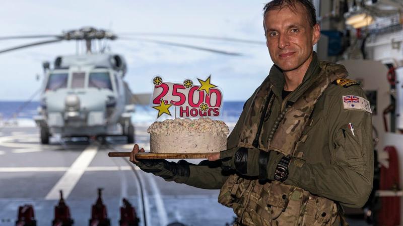 Lieutenant Michael Wisniewski receives a cake on board HMAS Brisbane after he clocked up 2500 career flying hours. Photo: Leading Seaman Daniel Goodman