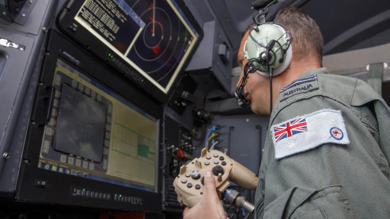 RAAF combat systems officer Flight Lieutenant Cameron McKinnon works at the C-130J Hercules aircraft's augmented crew station to capture imagery of the damage in Tonga. Photo: Sergeant David Gibbs.