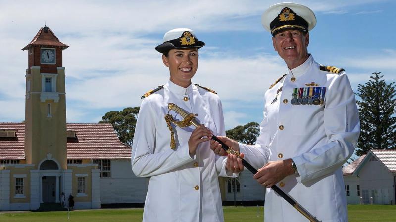 Commander Nick Barker passes on his father's ceremonial sword to his daughter, Lieutenant Emma Barker, following her graduation from New Entry Officers' Course at HMAS Creswell. Photo: Leading Seaman David Cox
