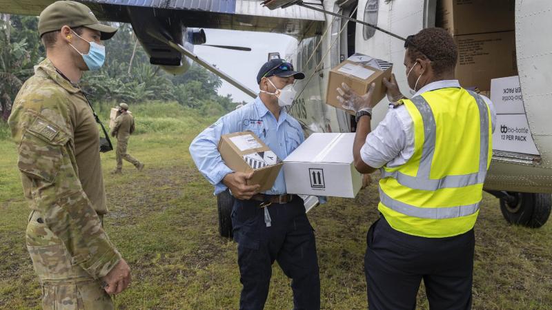 An Air Force aviator and an Australian Medical Assistance Team member help unload Australian Government critical aid supplies from the Solomon Airlines aircraft at Auki airport, Solomon Islands. Photo: Corporal Jarrod McAneney