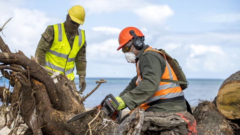 Republic of Fiji Military Forces engineer Sapper Saimoni Kamikamica, right, and Australian Army soldier Lance Corporal Kobie Rogers work together to clear a fallen tree on Atata Island, Tonga. Photo: Corporal Robert Whitmore.