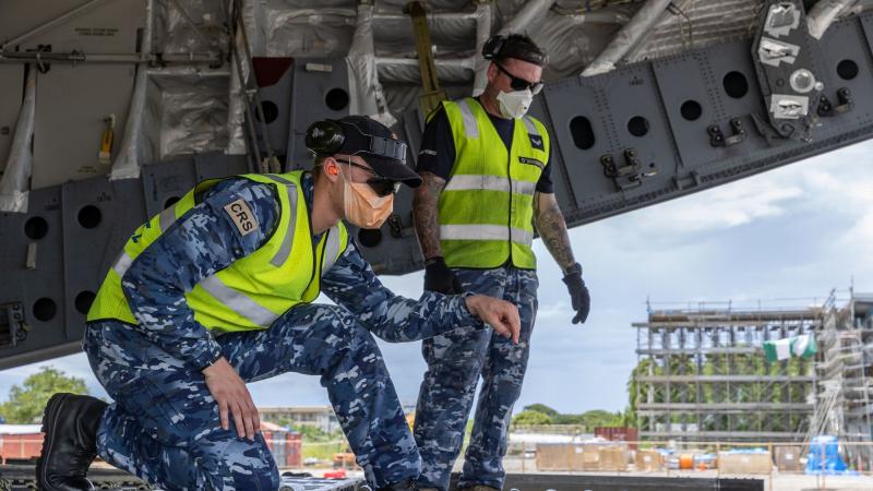 Aircraftsman Sam Schmidt, left, guides a forklift operator while unloading a C-17A Globemaster III aircraft at Honiara International Airport, Solomon Islands. Photo: Corporal Jarrod McAneney