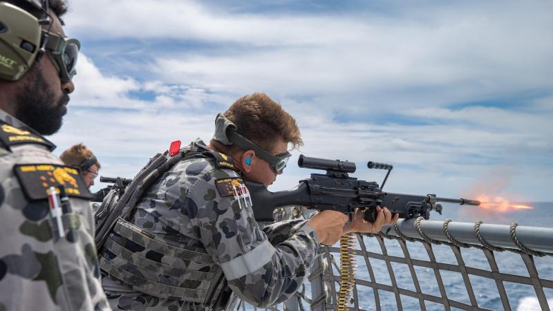 Leading Seaman Nathan Bob, left, directs Able Seaman Bradley Hocking as he fires an F89 Minimi on the flight deck of HMAS Arunta in the lead-up to the ship's regional presence deployment. Photo: Leading Seaman Sittichai Sakonpoonpol