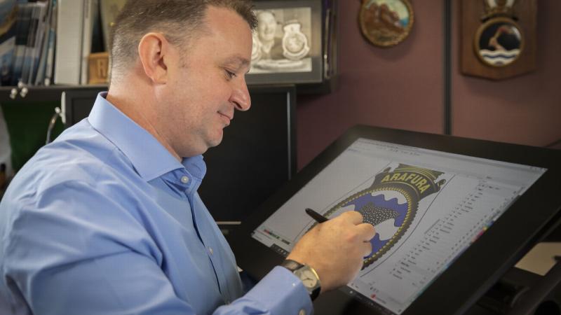 Manager Navy Badges, Paul 'Badger' Burnett, works on the NUSHIP Arafura badge in Canberra. Photo: Leading Seaman Kylie Jagiello