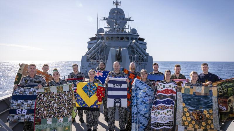HMAS Anzac crew deployed on Indo-Pacific Endeavour 2021 show the personalised quilts and laundry bags made for them by volunteers from Aussie Hero Quilts. Photo: Leading Seaman Leo Baumgartner