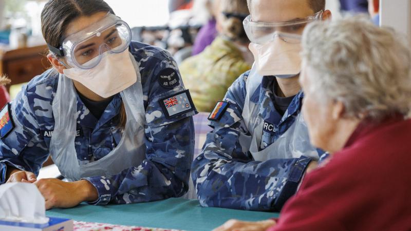 Royal Australian Air Force officer Pilot Officer Ruth Staer, left, and Pilot Officer Harry Allen talk with a resident at an aged-care facility in southern Tasmania as part of Operation COVID-19 Assist. Photo: Sergeant Cameron Pegg