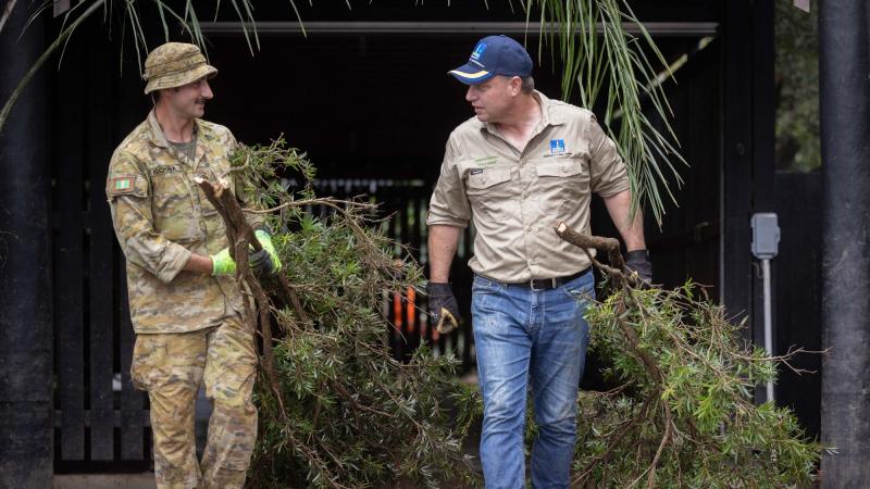 Private Rory Khochoba (left) from 6th Battalion, Royal Australian Regiment, working alongside the Lord Mayor of Brisbane, Adrian Schrinner, clearing debris from flood-damaged houses in Windsor, Brisbane. Photo: Corporal Jonathan Goedhart