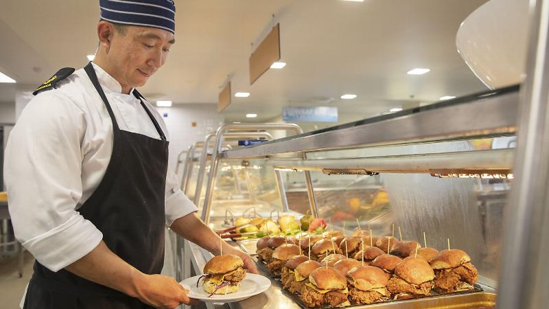 Royal Australian Navy catering supervisor Leading Seaman Tae Goh prepares to serve a Korean fried chicken burger at lunch in the HMAS Kuttabul main galley in Sydney. Photo: Corporal Jacob Joseph