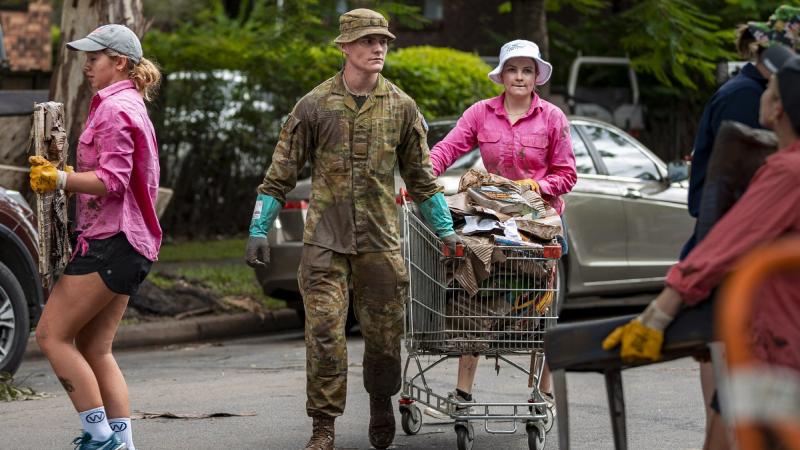 An Australian Army rifleman from 6th Battalion, Royal Australian Regiment, assists the local community to move flood-damaged belongings in St Lucia, Brisbane, during Operation Flood Assist 2022. Photo: Corporal Nicole Dorrett