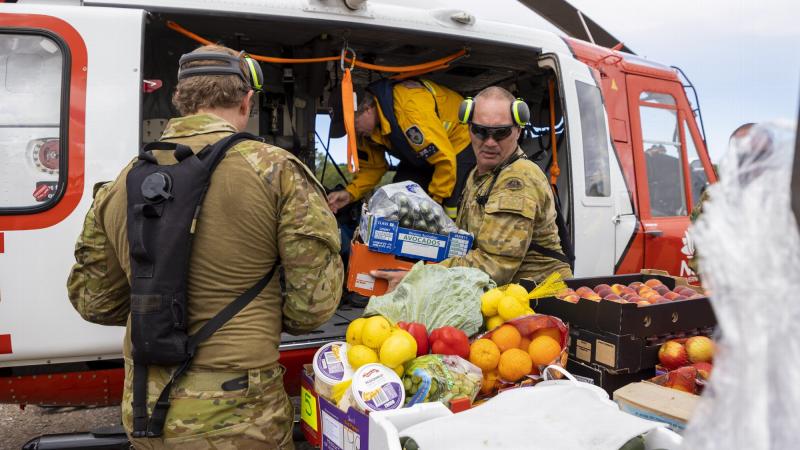 Sergeant Jody Cropp from 41st Battalion, Royal New South Wales Regiment loads crates of fresh food onto a helicopter operated by New South Wales Rural Fire Service, ready for delivery to areas of Northern NSW. Photo: Corporal Dustin Anderson