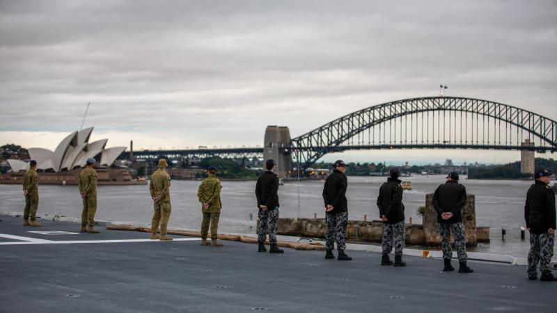 Australian Defence Force personnel on HMAS Adelaide line the flight deck as the ship returns to her home port of Fleet Base East in Sydney following a deployment on Operation Tonga Assist 2022. Photo: Petty Officer Christopher Szumlanski