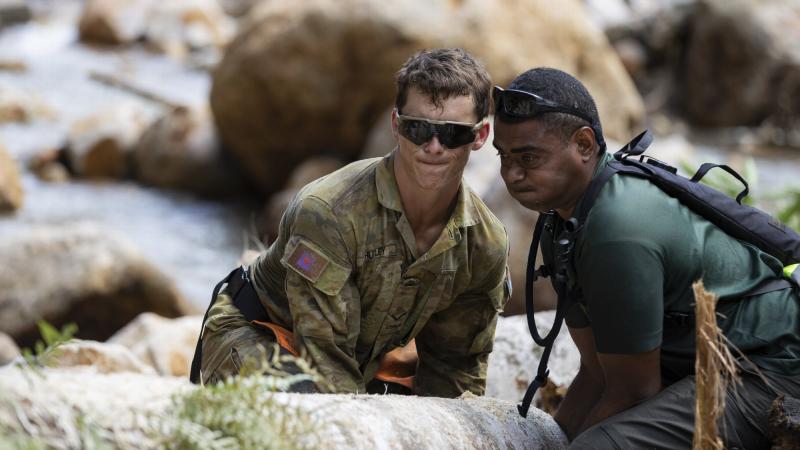 Australian and Fijian soldiers prepare to lift a log while rebuilding the Upper Wilsons Creek access road damaged by floodwaters in northern New South Wales. Photo: Corporal Sagi Biderman