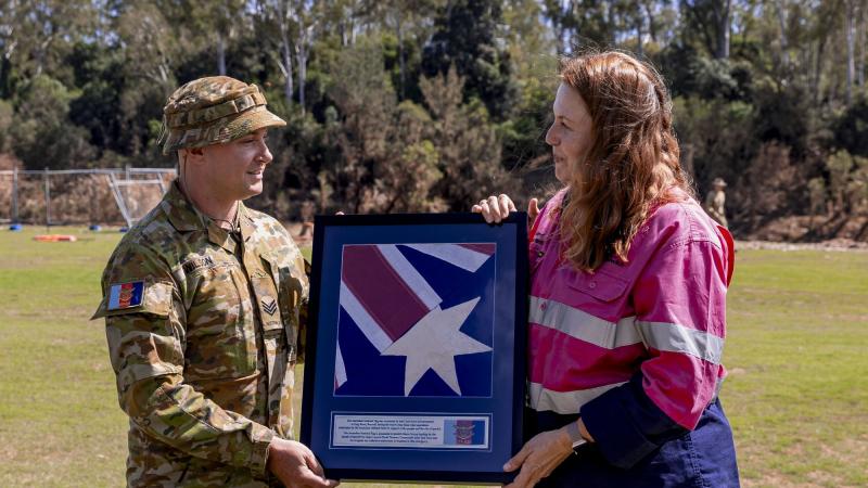 Sergeant Brad Wilson presents an Australian National Flag found in flood debris at Brassall to Ipswich City Mayor Teresa Harding during her visit to Colleges Crossing recreation reserve in Ipswich.  Corporal Nicole Dorrett