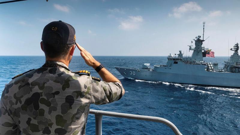 Commanding Officer HMAS Arunta Commander Samuel Woolrych salutes as Royal Malaysian Navy frigate KD Lekiu sails past. Photo: Leading Seaman Sittichai Sakonpoonpol