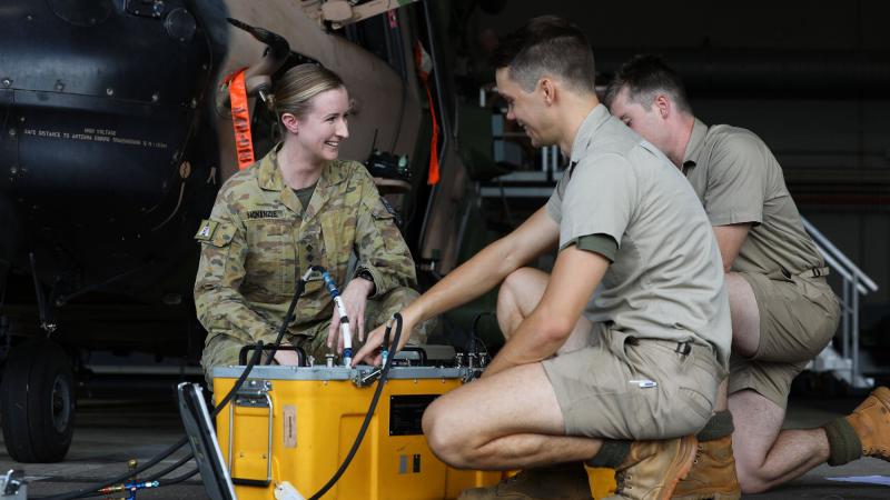 Captain Elise McKenzie, from 5th Aviation Regiment, talks to soldiers conducting maintenance on an MRH-90 Taipan at RAAF Base Townsville. Photo: Corporal Lisa Sherman