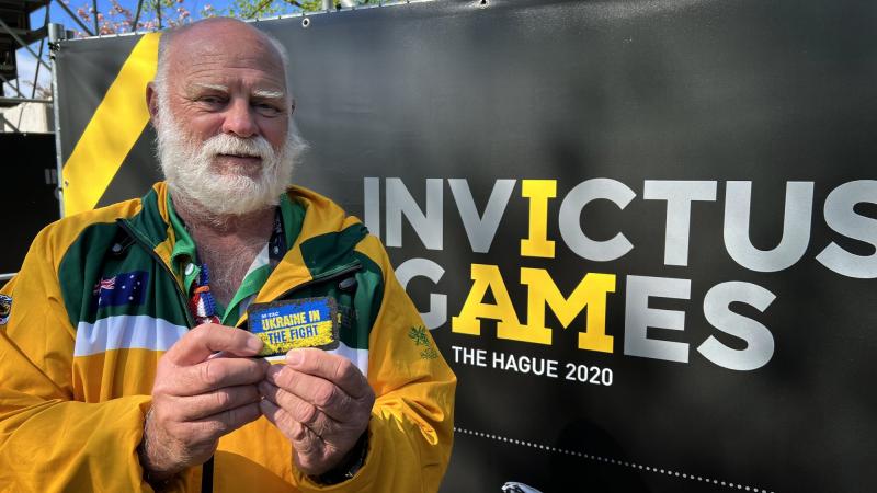 Proud father of Australian Invictus Games 2020 competitor and Royal Australian Navy sailor Leading Seaman Chris Reck, Bob Reck holds up a patch supporting Ukraine at Invictus Games Park in The Hague. Photo: Tina Langridge
