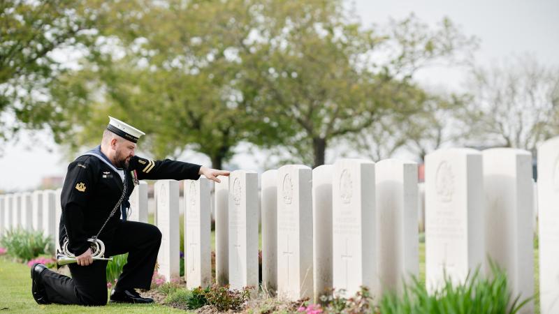 Able Seaman Mathew Tubman kneels at the grave of his relative, Private Mathew Tubman, at the Bonjean Military Cemetary in Lille, France. Photo: Corporal John Solomon