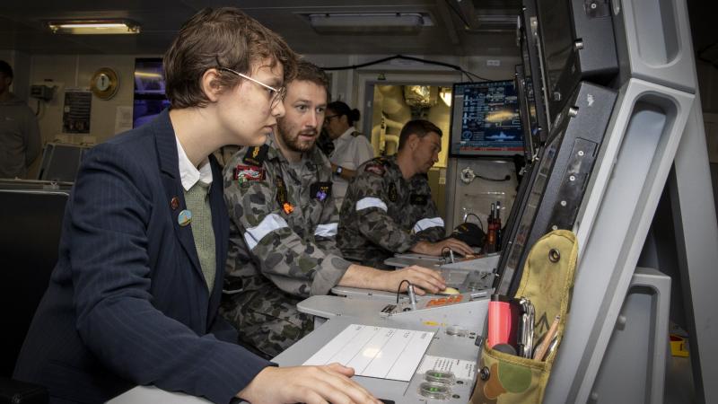Able Seaman Hamish Scott demonstrates HMAS Sydney's marine technical console to Madeleine Devitt during the Indo Pacific 2022 conference in Sydney. Photo: Leading Seaman Matthew Lyall