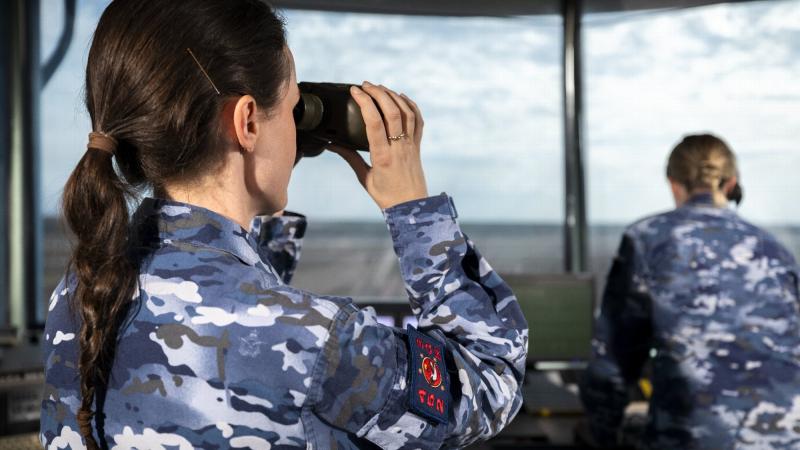 Royal Australian Air Force Air Traffic Controller, Flying Officer Charlotte Walsh (left) from No. 452 Squadron, spots an incoming aircraft at RAAF Base Tindal in the Northern Territory, during Exercise Diamond Storm 2022