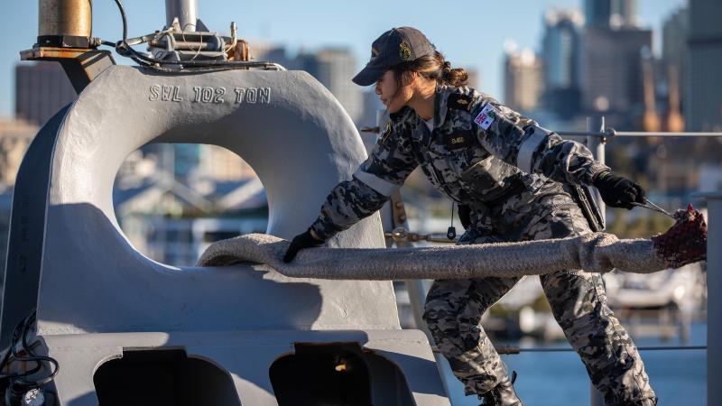 Able Seaman Boatwain Mate Linda Emelio handles lines on the quarterdeck of HMAS Canberra while departing Fleet Base East in Sydney. Photo: Petty Officer Christopher Szumlanski