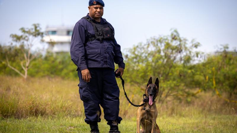 Senior Constable Adrien Lamu and working dog Nym from the RPNGC K-9 unit prepare to board a RAAF C-27J Spartan as part of Operation Kimba. Photo: Corporal Jonathan Goedhart