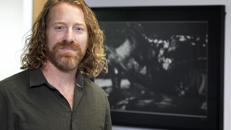 Retired Australian Army officer and artist Mike Armstrong stands in front of a photograph he produced as part of a photographic exhibition titled 'Voices of Veterans' at the National Press Gallery in Canberra.
