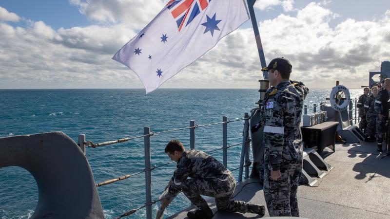 Executive Officer HMAS Canberra Commander Justin Cloney scatters the ashes of former Navy navigation officer, Captain Michael Freeman, during a committal of ashes to the sea ceremony. Photo: Petty Officer Christopher Szumlanski