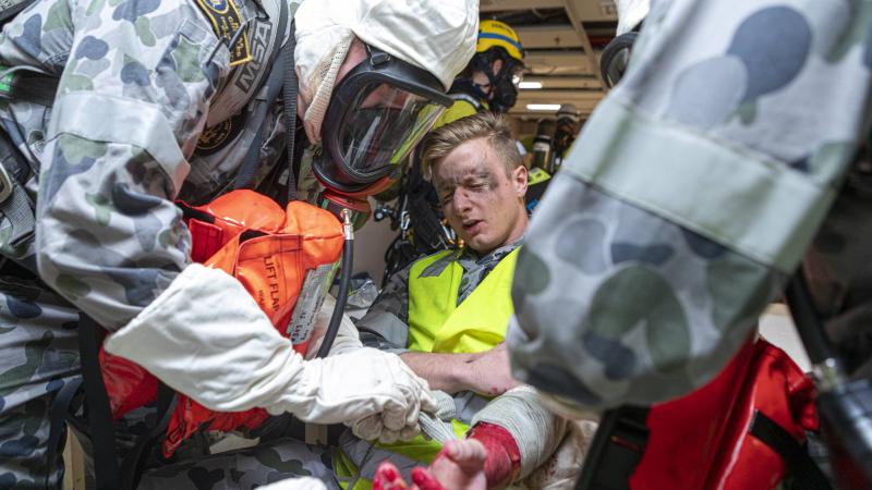 Navy personnel act as first responders during a simulated emergency on board HMAS Choules berthed at Fleet Base East in Sydney. Photo: Able Seaman Benjamin Ricketts