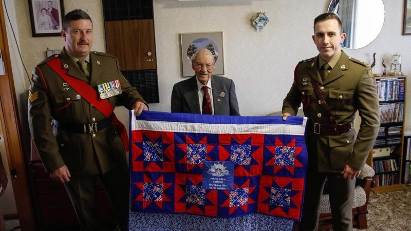 Lieutenant Kurt O’Neill and Sergeant Steven Banks, from the School of Armour, present WW2 veteran, 101-year-old Bertram (Bert) Sutton, with an Aussie Hero Quilt at his home in Numurkah, Victoria.