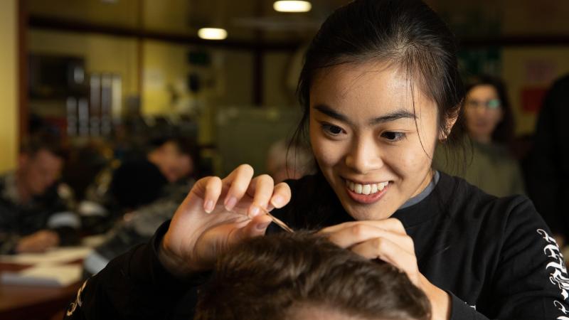 Macquarie University researcher Madison Kho takes a hair sample from a HMAS Canberra crew member to measure cortisol levels. Photo: Leading Seaman Matthew Lyall