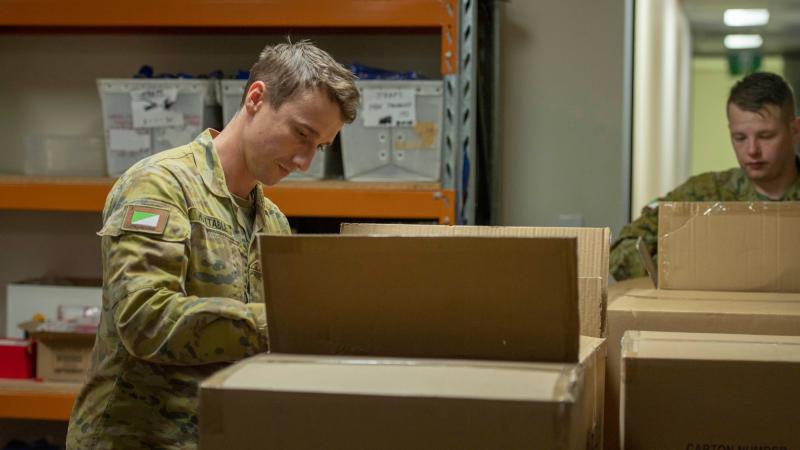 Two members from 7th Brigade labelling which of the many Legacy bears they're packing, with options ranging from Army to Navy to Royal Australian Air Force. Photo: Captain Cody Tsaousis