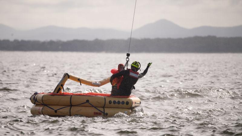 A member of Air Force's No. 2 Squadron is winched from a life raft on Nelson Bay to a search and rescue helicopter during a survival training exercise. Photo: Lieutenant Samuel Hicks