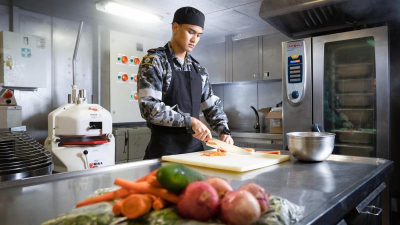Maritime Logistics Chef Able Seaman Zachary Galit prepares vegetables in the galley of HMAS Canberra during Exercise Rim of the Pacific (RIMPAC) 2022 in the Pacific Ocean. Photo: Leading Seaman Matthew Lyall