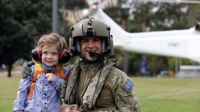 Australian Army Aircrewman Corporal Matthew Nebauer and young Olivia get ready for a flight on a Helicorp-leased Leonardo AW139 helicopter during Exercise Care Bear at James Cook University oval in Townsville. Photo: Captain Carolyn Barnett