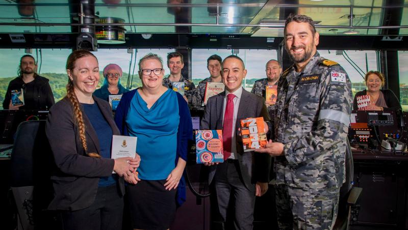 Library Manager Kym Andrews, left, Librarian Penelope Sherrell, Assistant Director Defence Archives and Services Centre Michael Chow and Commander Steve McCracken with donated library books on the bridge of HMAS Stalwart. Photo: Petty Officer Richard Cord