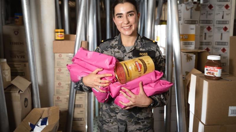 Maritime Logistics Officer Sub-Lieutenant Amelia Ross holds an assortment of coffee products in the dry store of HMAS Canberra during Exercise Rim of the Pacific (RIMPAC) 2022 in the Pacific Ocean. Photo: Leading Seaman Matthew Lyall